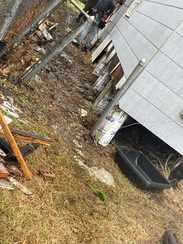 Side of a raised house with wood shoring posts supporting the frame while crawl space supports are replaced